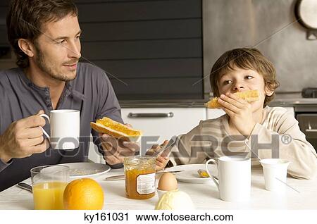 Mid adult man having breakfast with his son View Large Photo Image Stock Image - Mid adult man having breakfast with his son. Fotosearch