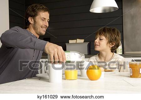 Mid adult man having breakfast with his son in the kitchen View Large Photo Image Stock Photo - Mid adult man having breakfast with his son in the kitchen. Fotosearch