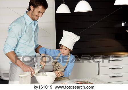 Stock Photo - Mid adult man making a cake with his son in the kitchen. Fotosearch