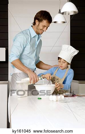 Mid adult man making a cake with his son in the kitchen View Large Photo Image Stock Photography - Mid adult man making a cake with his son in the kitchen. Fotosearch