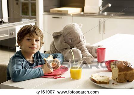 Portrait of a boy having breakfast in the kitchen View Large Photo Image Stock Photo - Portrait of a boy having breakfast in the kitchen. Fotosearch