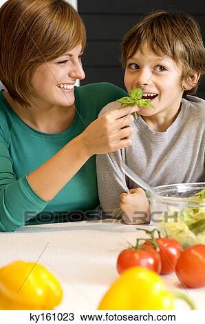 Young woman feeding basil to her son View Large Photo Image Stock Image - Young woman feeding basil to her son. Fotosearch