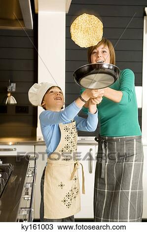 Young woman flipping a pancake with her son View Large Photo Image Stock Image - Young woman flipping a pancake with her son. Fotosearch