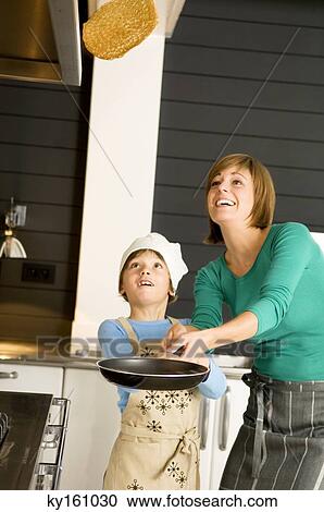 Young woman flipping a pancake with her son View Large Photo Image Stock Image - Young woman flipping a pancake with her son. Fotosearch