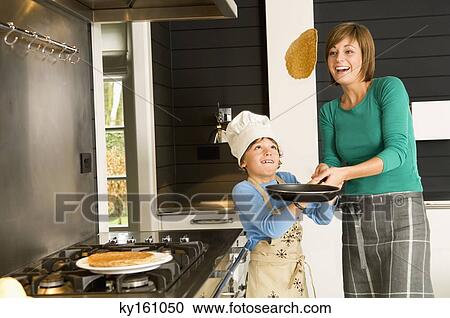 Young woman flipping a pancake with her son View Large Photo Image Stock Image - Young woman flipping a pancake with her son. Fotosearch