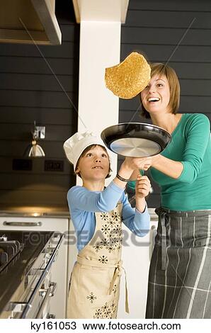Young woman flipping a pancake with her son View Large Photo Image Stock Image - Young woman flipping a pancake with her son. Fotosearch