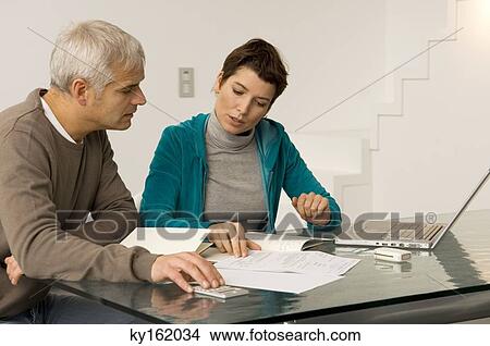 Picture - Mature man and a mid adult woman planning their finances. Fotosearch