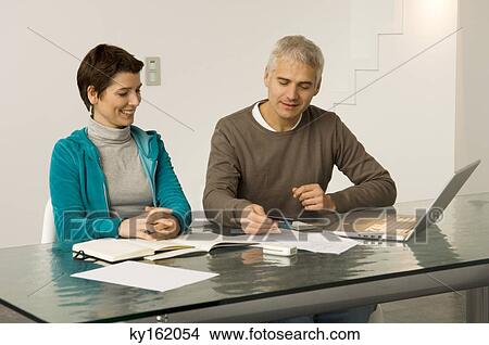 Mature man and a mid adult woman working on a laptop and holding a credit card View Large Photo Image Picture - Mature man and a mid adult woman working on a laptop and holding a credit card. Fotosearch