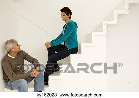 Mature man and a mid adult woman sitting on a staircase and looking at each other View Large Photo Image Stock Photo - Mature man and a mid adult woman sitting on a staircase and looking at each other. Fotosearch