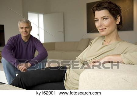 Mid adult woman and a mature man sitting in a living room View Large Photo Image Stock Image - Mid adult woman and a mature man sitting in a living room. Fotosearch