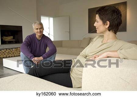 Mid adult woman and a mature man sitting in a living room View Large Photo Image Stock Image - Mid adult woman and a mature man sitting in a living room. Fotosearch