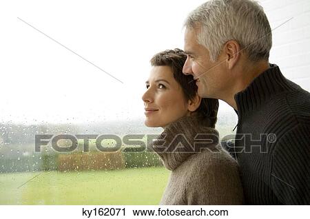 Mid adult woman and a mature man standing by a window View Large Photo Image Stock Image - Mid adult woman and a mature man standing by a window. Fotosearch