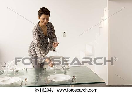 Mid adult woman setting a dining table View Large Photo Image Stock Photo - Mid adult woman setting a dining table. Fotosearch