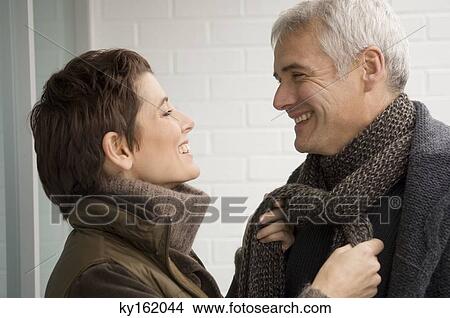 Picture - Mid adult woman tying a mature man's scarf. Fotosearch