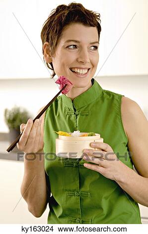 Close-up of a mid adult woman eating food with chopsticks View Large Photo Image Picture - Close-up of a mid adult woman eating food with chopsticks. Fotosearch