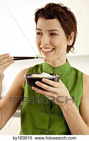 Close-up of a mid adult woman eating rice with chopsticks View Large Photo Image Stock Photography - Close-up of a mid adult woman eating rice with chopsticks. Fotosearch