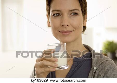 Close-up of a mid adult woman holding a glass of milk View Large Photo Image Stock Photo - Close-up of a mid adult woman holding a glass of milk. Fotosearch