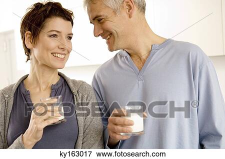 Mature man and a mid adult woman holding glasses of milk View Large Photo Image Stock Photo - Mature man and a mid adult woman holding glasses of milk. Fotosearch