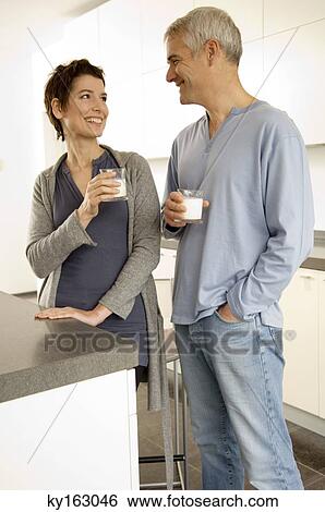 Stock Photograph - Mature man and a mid adult woman holding glasses of milk. Fotosearch