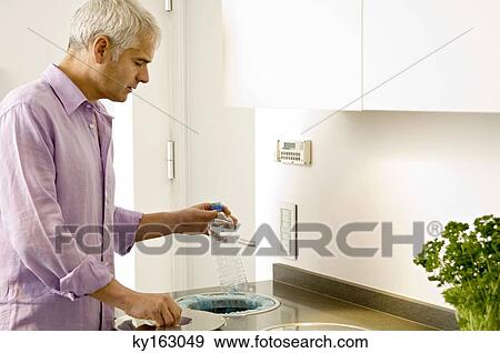 Mature man scraping a water bottle into a garbage bin View Large Photo Image Stock Photo - Mature man scraping a water bottle into a garbage bin. Fotosearch