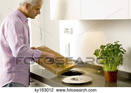 Mature man scraping vegetables pieces into a garbage bin View Large Photo Image Stock Image - Mature man scraping vegetables pieces into a garbage bin. Fotosearch