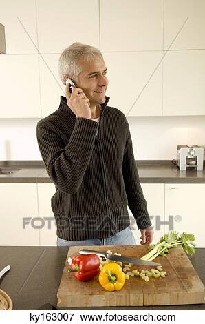 Mature man talking on a mobile phone in the kitchen View Large Photo Image Stock Photo - Mature man talking on a mobile phone in the kitchen. Fotosearch