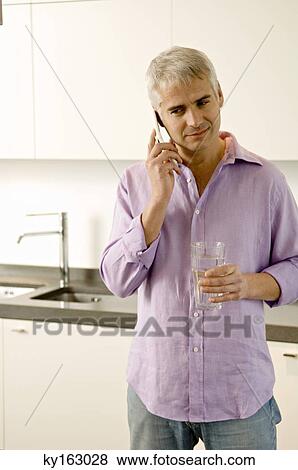Mature man talking on a mobile phone in the kitchen View Large Photo Image Stock Photo - Mature man talking on a mobile phone in the kitchen. Fotosearch