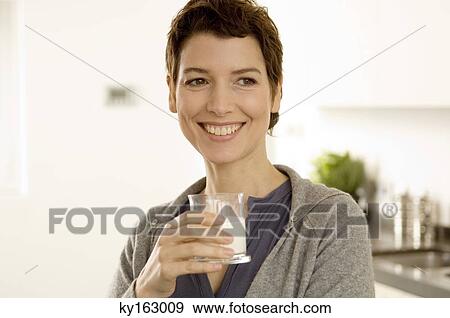 Mid adult woman holding a glass of milk View Large Photo Image Stock Photo - Mid adult woman holding a glass of milk. Fotosearch