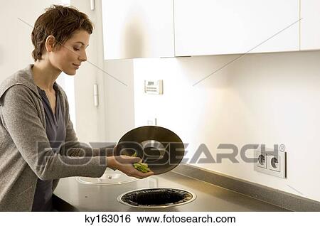 Mid adult woman scraping vegetables pieces into a garbage bin View Large Photo Image Stock Photograph - Mid adult woman scraping vegetables pieces into a garbage bin. Fotosearch