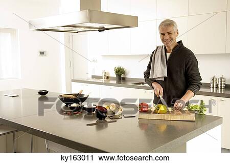 Portrait of a mature man chopping vegetables in the kitchen View Large Photo Image Stock Image - Portrait of a mature man chopping vegetables in the kitchen. Fotosearch