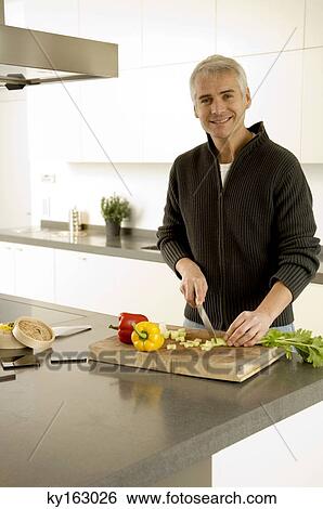 Portrait of a mature man chopping vegetables in the kitchen View Large Photo Image Stock Photograph - Portrait of a mature man chopping vegetables in the kitchen. Fotosearch