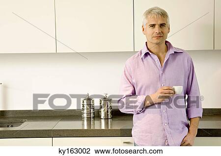 Portrait of a mature man holding a cup of tea in the kitchen View Large Photo Image Stock Image - Portrait of a mature man holding a cup of tea in the kitchen. Fotosearch