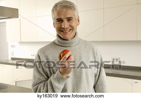 Portrait of a mature man holding an apple View Large Photo Image Stock Photo - Portrait of a mature man holding an apple. Fotosearch