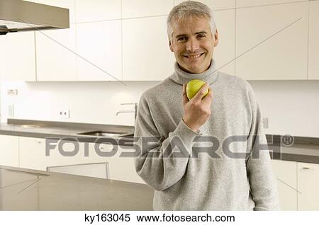 Portrait of a mature man holding an apple View Large Photo Image Stock Photography - Portrait of a mature man holding an apple. Fotosearch