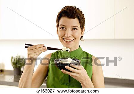 Portrait of a mid adult woman eating rice with chopsticks View Large Photo Image Stock Photo - Portrait of a mid adult woman eating rice with chopsticks. Fotosearch