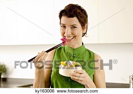 Portrait of a mid adult woman eating food with chopsticks View Large Photo Image Stock Photograph - Portrait of a mid adult woman eating food with chopsticks. Fotosearch