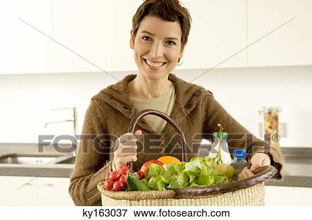 Portrait of a mid adult woman holding a basket of fruits and vegetables View Large Photo Image Stock Photo - Portrait of a mid adult woman holding a basket of fruits and vegetables. Fotosearch