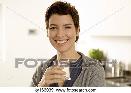 Stock Photo - Portrait of a mid adult woman holding a glass of milk. Fotosearch