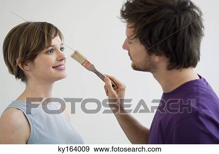 Close-up of a mid adult man applying paint on a young woman's nose View Large Photo Image Stock Photo - Close-up of a mid adult man applying paint on a young woman's nose. Fotosearch