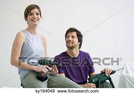 Mid adult man and a young woman holding drills and smiling View Large Photo Image Stock Photo - Mid adult man and a young woman holding drills and smiling. Fotosearch