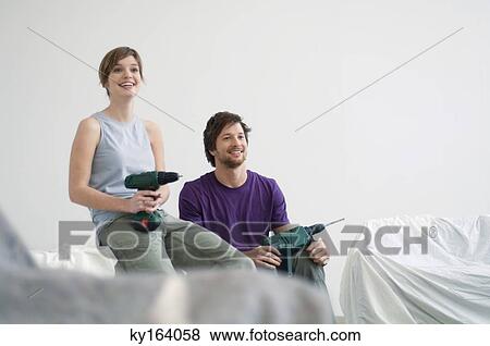 Mid adult man and a young woman holding drills View Large Photo Image Stock Photo - Mid adult man and a young woman holding drills. Fotosearch