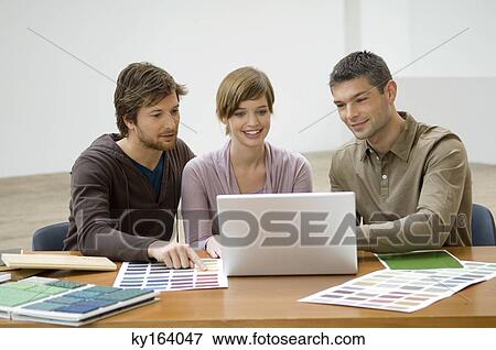 Mid adult man and a young woman discussing with an interior designer View Large Photo Image Stock Photo - Mid adult man and a young woman discussing with an interior designer. Fotosearch