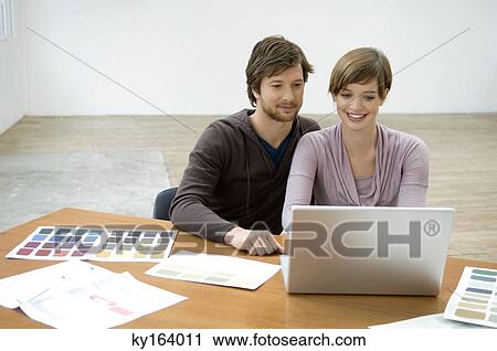 Mid adult man and a young woman using a laptop and smiling View Large Photo Image Stock Image - Mid adult man and a young woman using a laptop and smiling. Fotosearch
