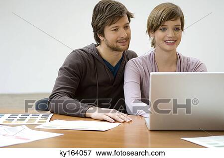 Mid adult man and a young woman using a laptop and smiling View Large Photo Image Stock Photo - Mid adult man and a young woman using a laptop and smiling. Fotosearch