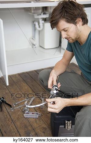 Mid adult man repairing a faucet in the kitchen View Large Photo Image Stock Photo - Mid adult man repairing a faucet in the kitchen. Fotosearch