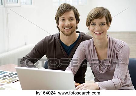Picture - Portrait of a mid adult man and a young woman using a laptop. Fotosearch