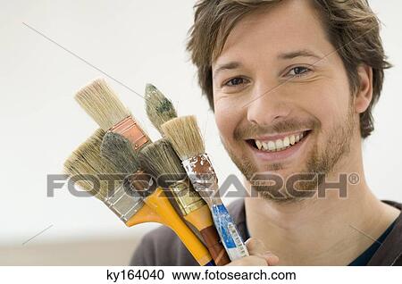 Portrait of a mid adult man holding paintbrushes View Large Photo Image Stock Image - Portrait of a mid adult man holding paintbrushes. Fotosearch