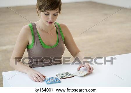 Young woman looking at tiles on a table View Large Photo Image Stock Photo - Young woman looking at tiles on a table. Fotosearch
