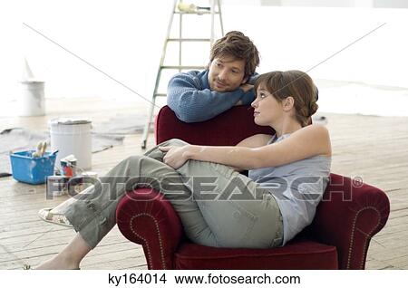 Young woman sitting in an armchair and a mid adult man leaning behind her View Large Photo Image Picture - Young woman sitting in an armchair and a mid adult man leaning behind her. Fotosearch