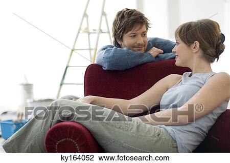 Young woman sitting in an armchair and a mid adult man leaning behind her View Large Photo Image Stock Image - Young woman sitting in an armchair and a mid adult man leaning behind her. Fotosearch